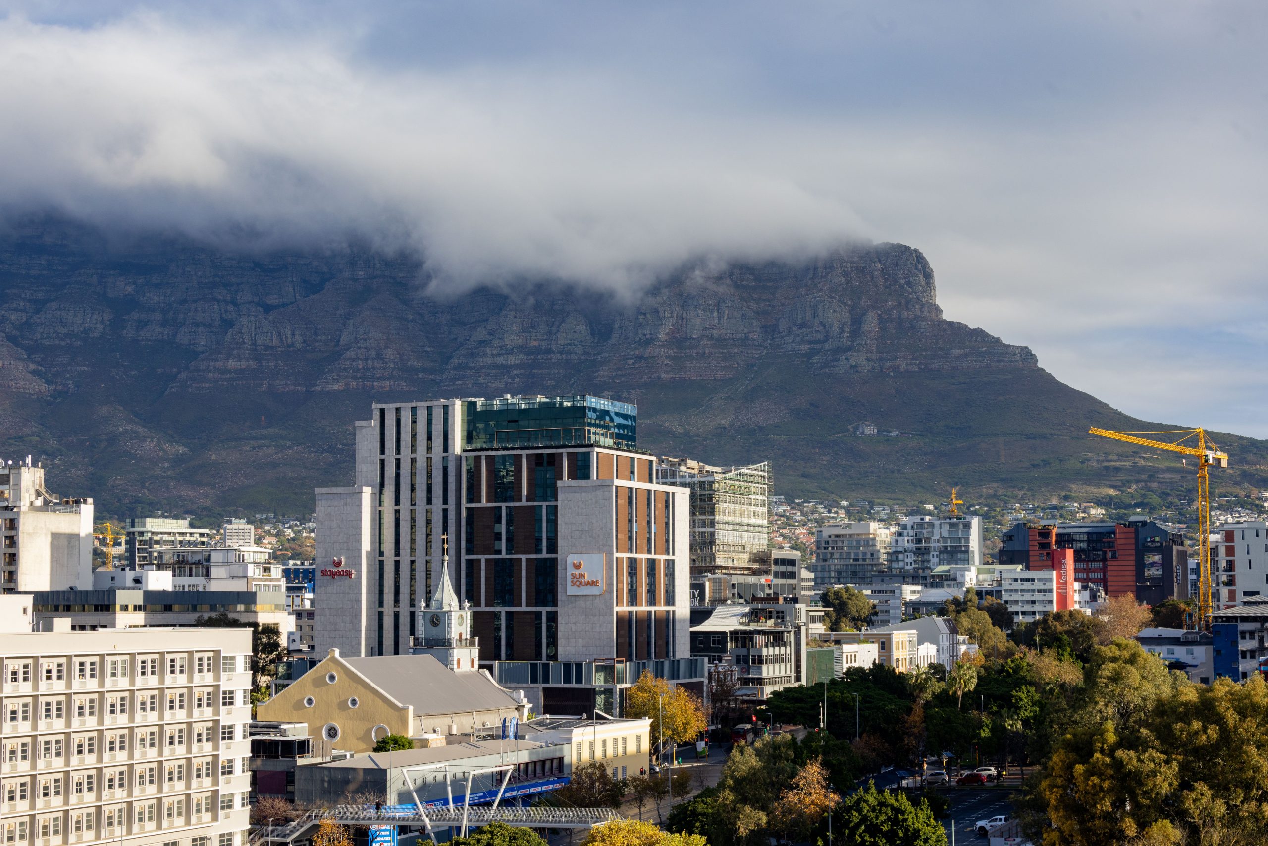 A beautiful view of Cape Town's skyline with iconic Table Mountain under a cloudy sky.