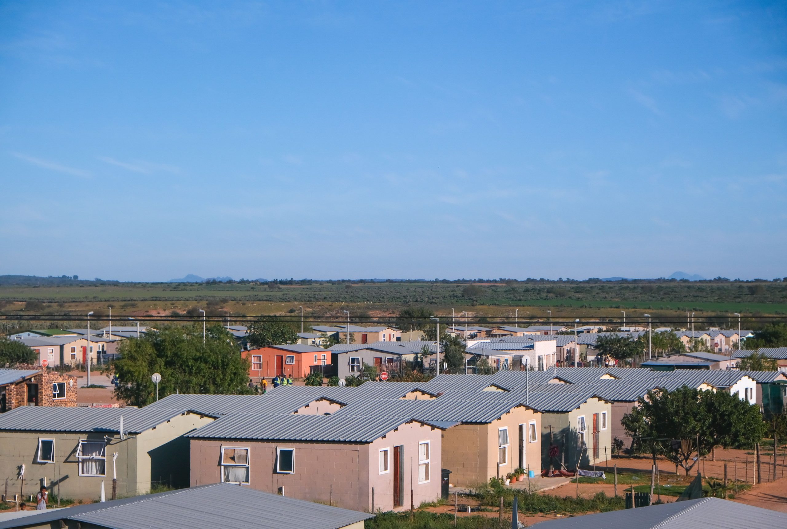 Aerial view showing concrete houses in a peaceful small town under a clear blue sky.